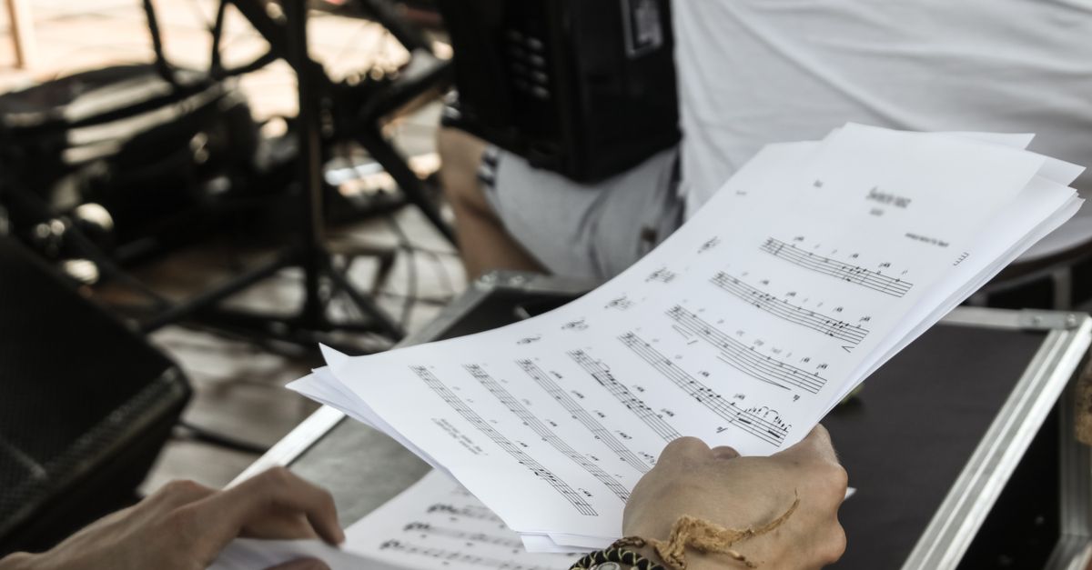 Close-up of musician's hands with sheet music during a rehearsal in a studio setting.